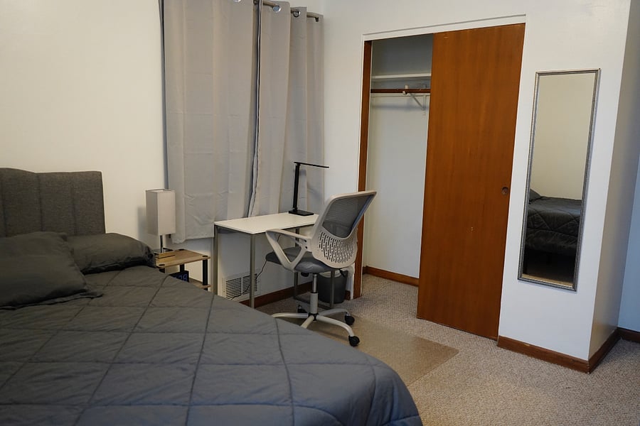 Master bedroom. Blackout curtains, desk, alarm clock.