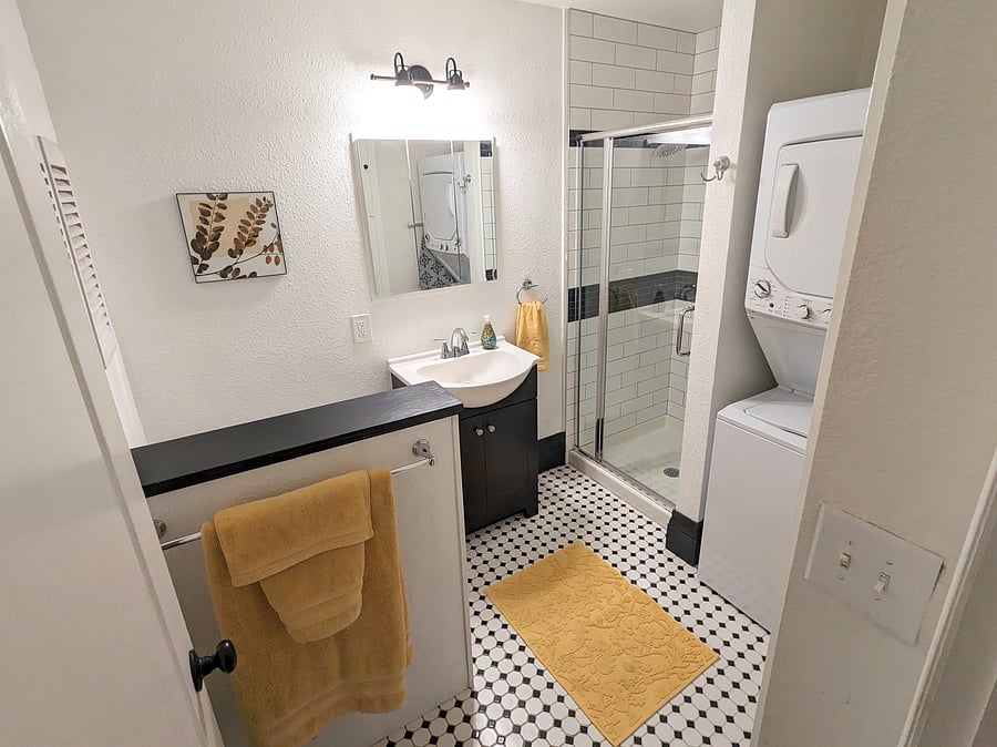 Remodeled main bathroom off the hallway. Includes stacked washer/dryer, shower, toilet, sink.