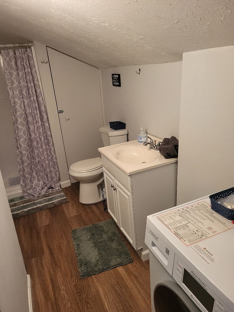 Bathroom upstairs off bedroom. Shower, single vanity and toilet with medicine cabinet/mirror on wall opposite vanity. Combo washer/dryer in bathroom. 