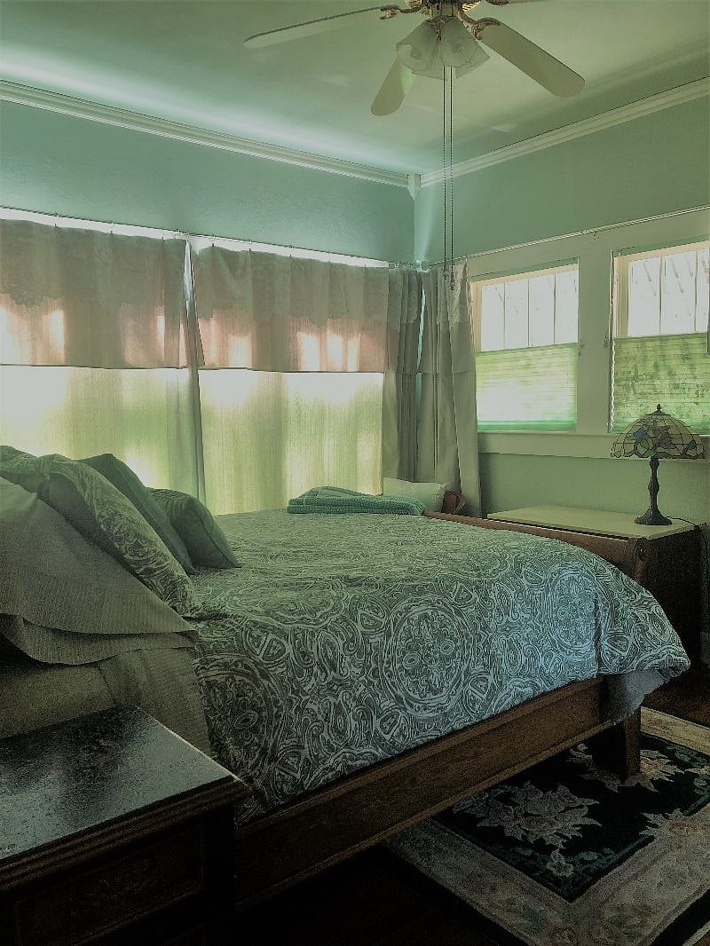 Bedroom with Queen sleigh bed, cushion-top mattress, two bedside tables, dresser, two side lamps, ceiling fan with lamps, closet with hanging rod, upper shelf, and storage pockets. Sheets are refreshed weekly.