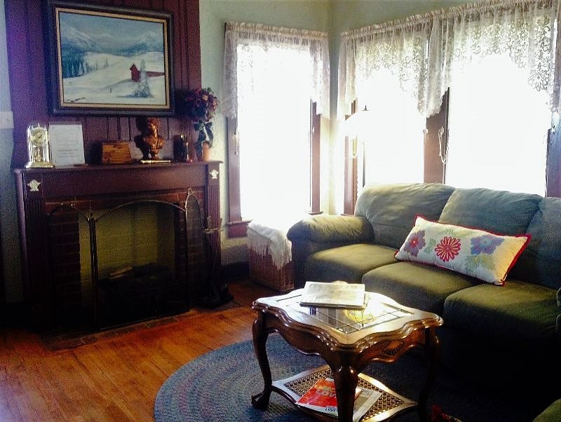Living Room with gas log fireplace, couch, loveseat, built in desk/bookcase, entry to small balcony