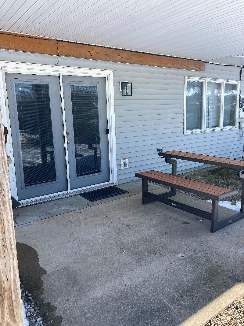 An entrance into the unit. A large bedroom window on the right, and a picnic table convertible to a bench..