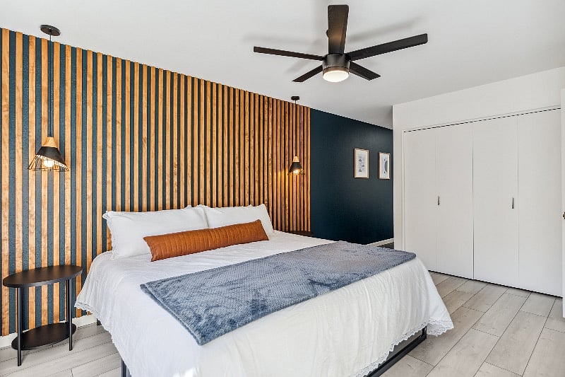 Newly renovated primary bedroom with multiple closets, smart tv, and cool accent wood wall.