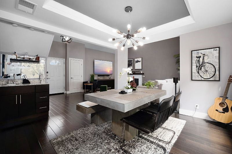 Step into a modern dining space anchored by a sleek concrete table and illuminated by a stylish chandelier.
A convenient mini bar enhances entertaining, while the large windows frame lush patio greenery, bringing a vibrant touch of nature indoors.