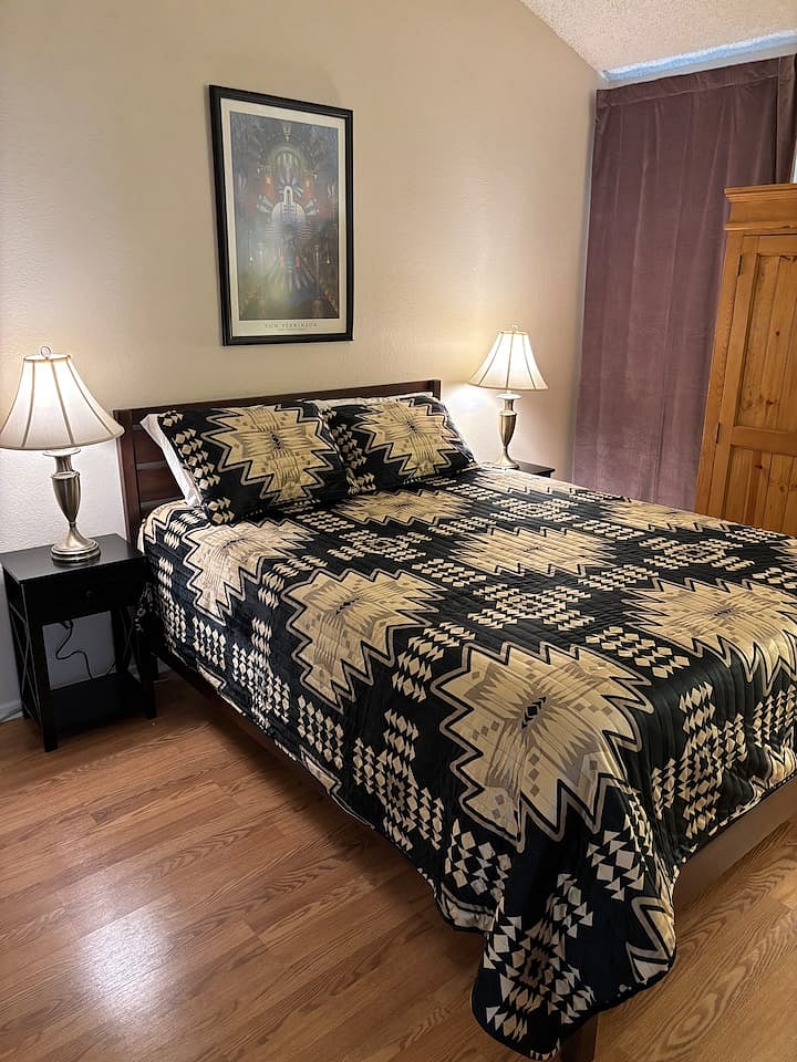 Comfortable second bedroom with queen bed, private bathroom, smart TV, large wardrobe, and office nook.