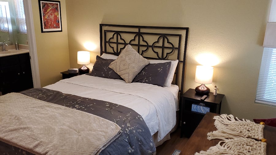 Main bedroom with en-suite bathroom, walk-in closet, dresser, smart TV and two seating areas.
