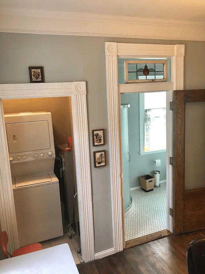 Standing in front of fridge looking into stackable washer/dryer and bathroom.