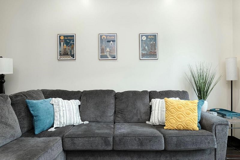 Well-lit living room with smart TV, comfy sofa and papasan, and blackout curtains for reflection-free TV! Office space is to the left of the sofa: a desk, swivel office chair and screen.