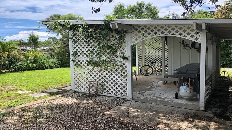 Backyard covered area with lawn chairs, charcoal & gas grill and 2 bikes