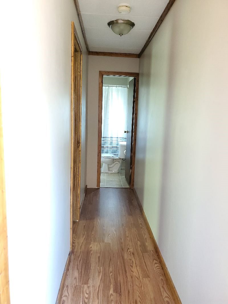 Hallway to the right of the front door leading to the first bed room and full bath at the end of the hall.