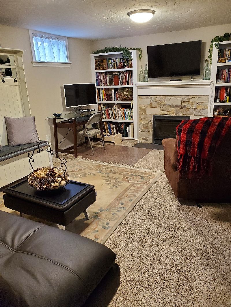 Large livingroom with desk, futon couch, easy chair and gas fireplace.