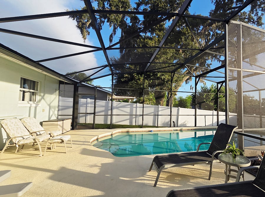 The backyard swimming pool is encased in a protective cage, keeping bugs at bay and ensuring a pleasant, uninterrupted swim experience.