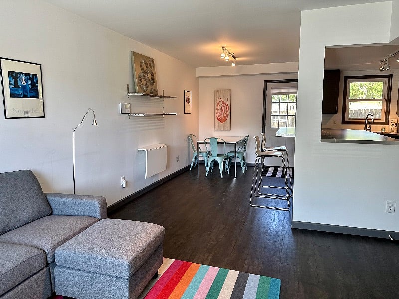 View walking in front door, open floor plan, living room with Roku tv, dining area for 4, island with two bar stools, full kitchen 
