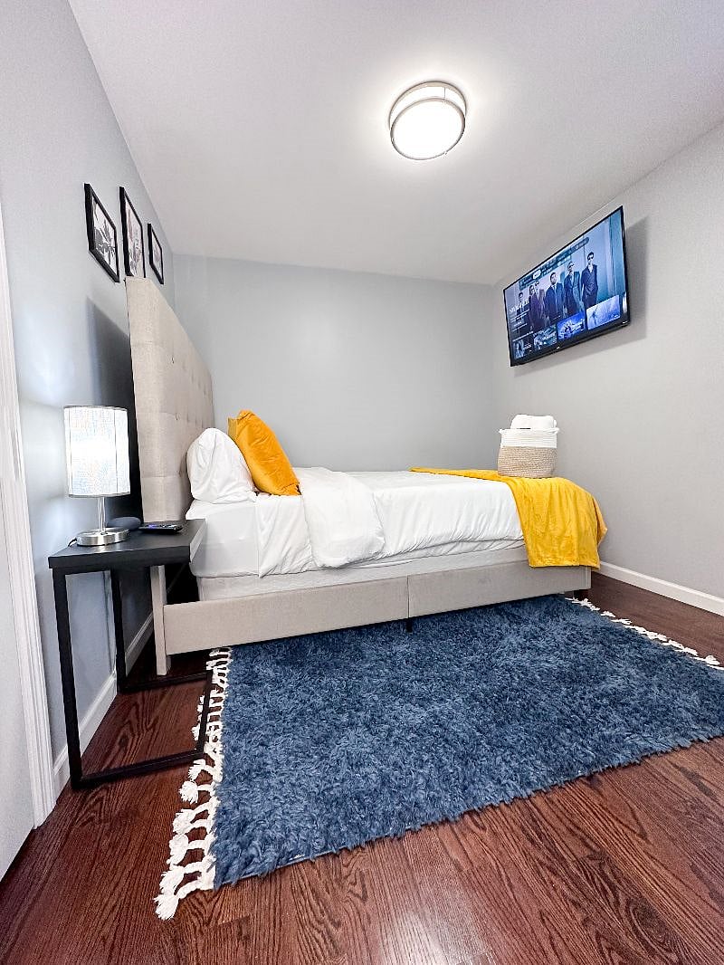 Bedroom 3 with a Queen-sized bed, 50-inch Smart TV, charging lamp, and virtual assistant/speaker