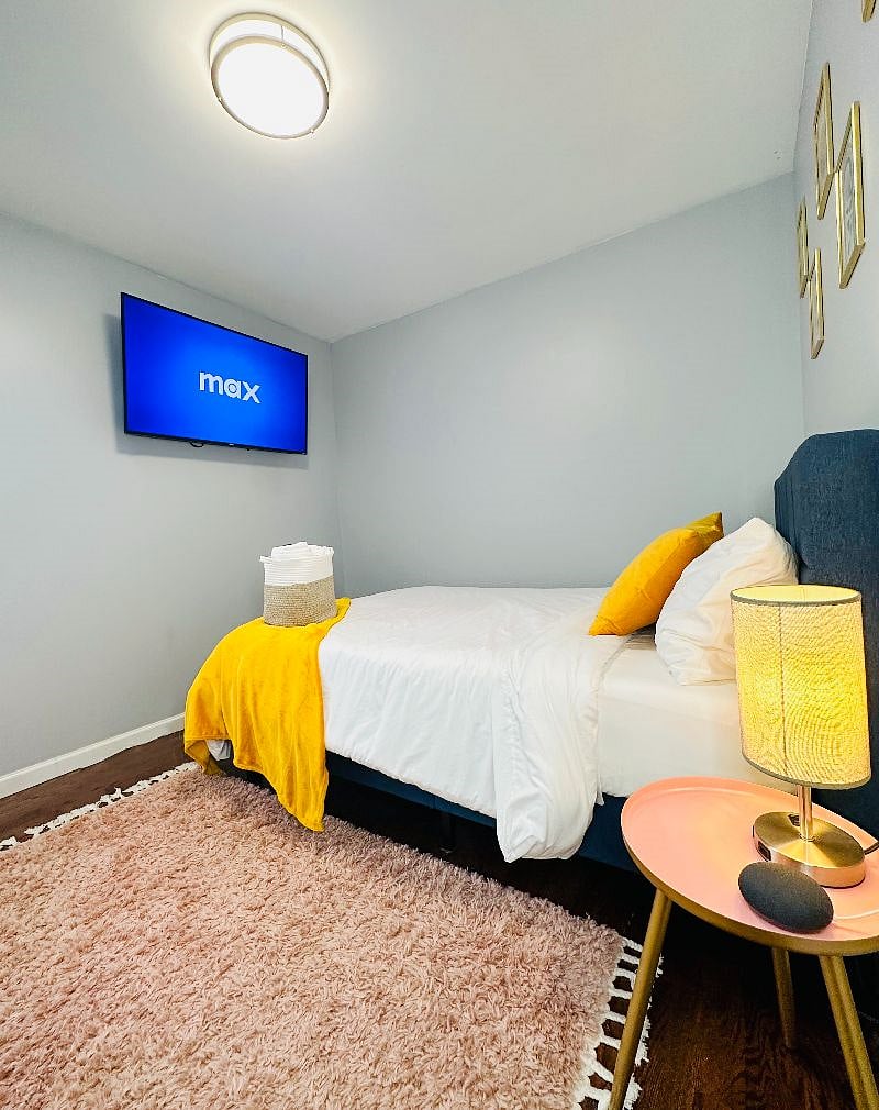 Bedroom 2 with a Full-sized bed, 50-inch Smart TV, charging lamp, and virtual assistant/speaker