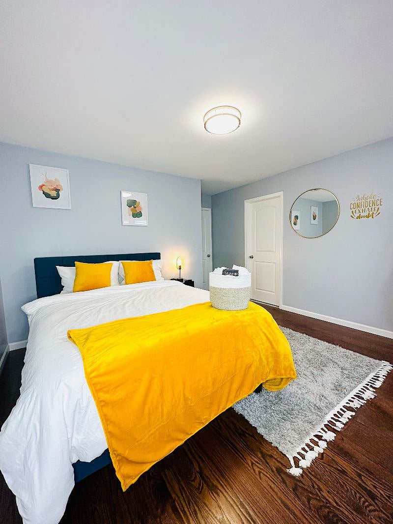 Bedroom 1 with a Queen-sized bed, 50-inch Smart TV, charging lamp, virtual assistant/speaker, and en-suite bathroom