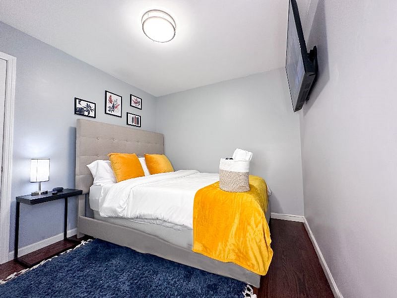 Bedroom 3 with a Queen-sized bed, 50-inch Smart TV, charging lamp, and virtual assistant/speaker