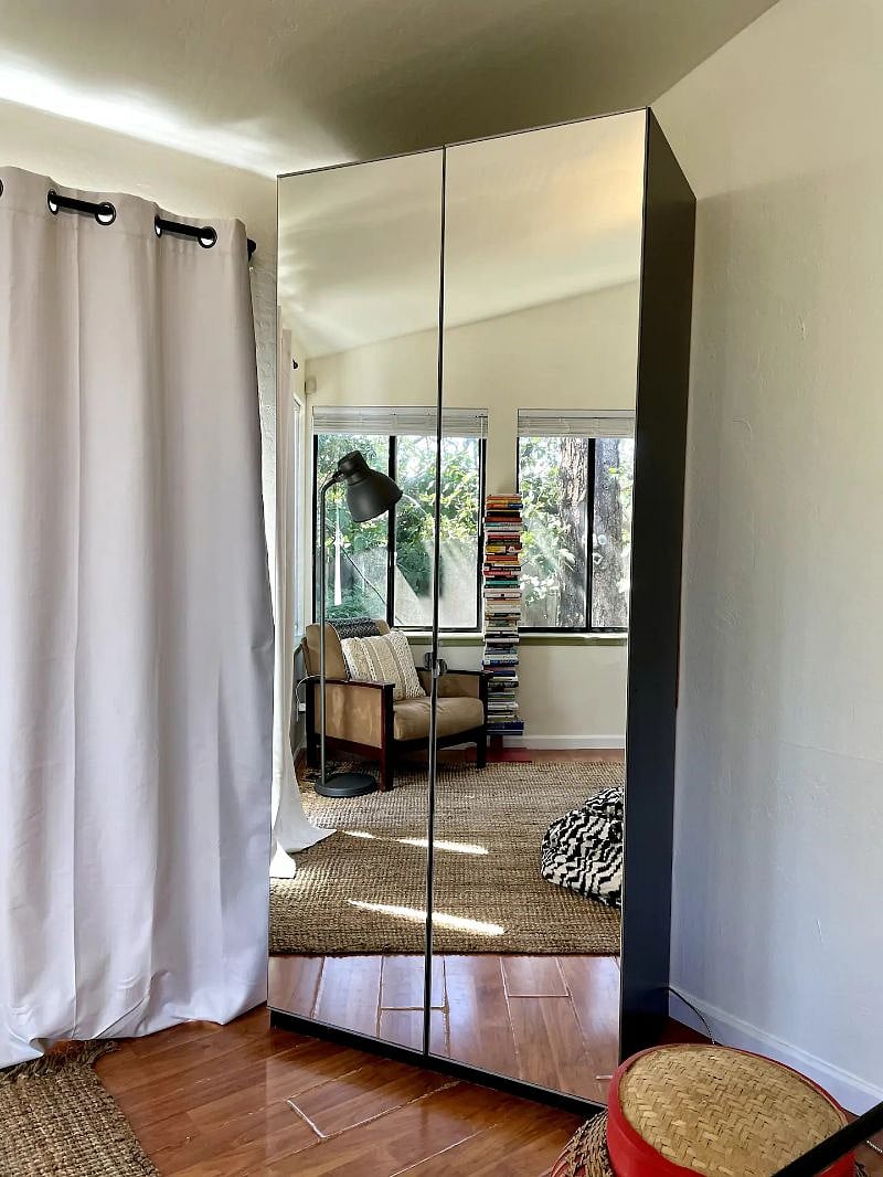 A floor-to-ceiling wardrobe with double-doors, which a full-length mirror that magnifies the space.