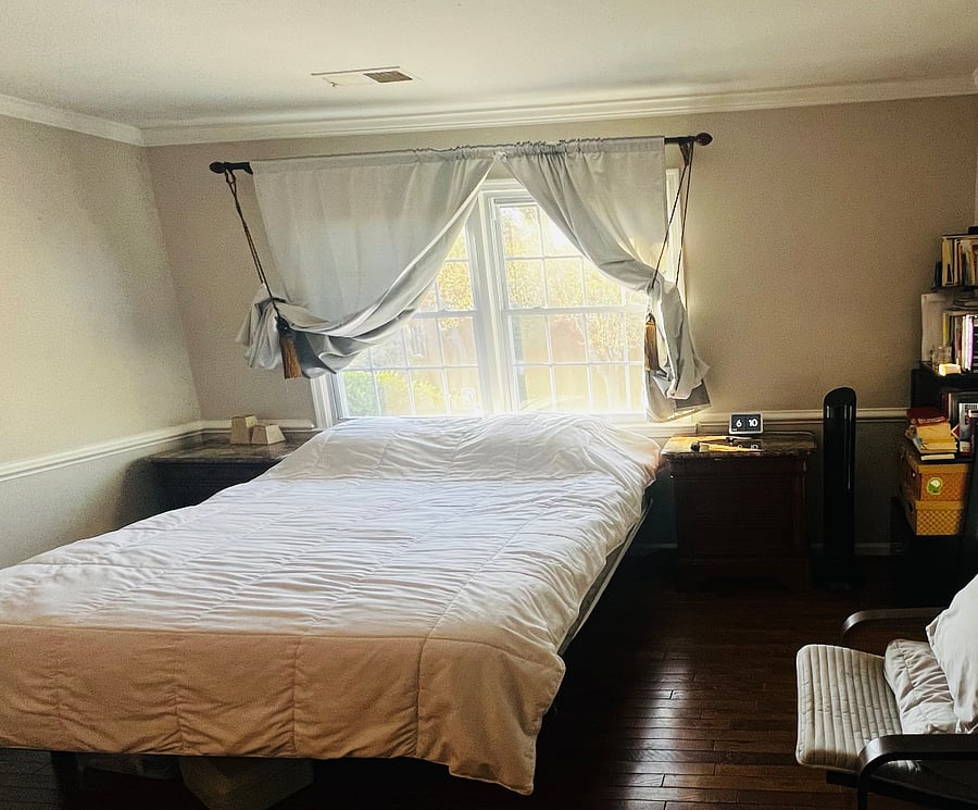 Primary Bedroom with two night stands, medium-firm king size bed, sitting chair, 65" TV, desk, chair and 6-drawer dresser with mirror. Hardwood floors, bright windows.