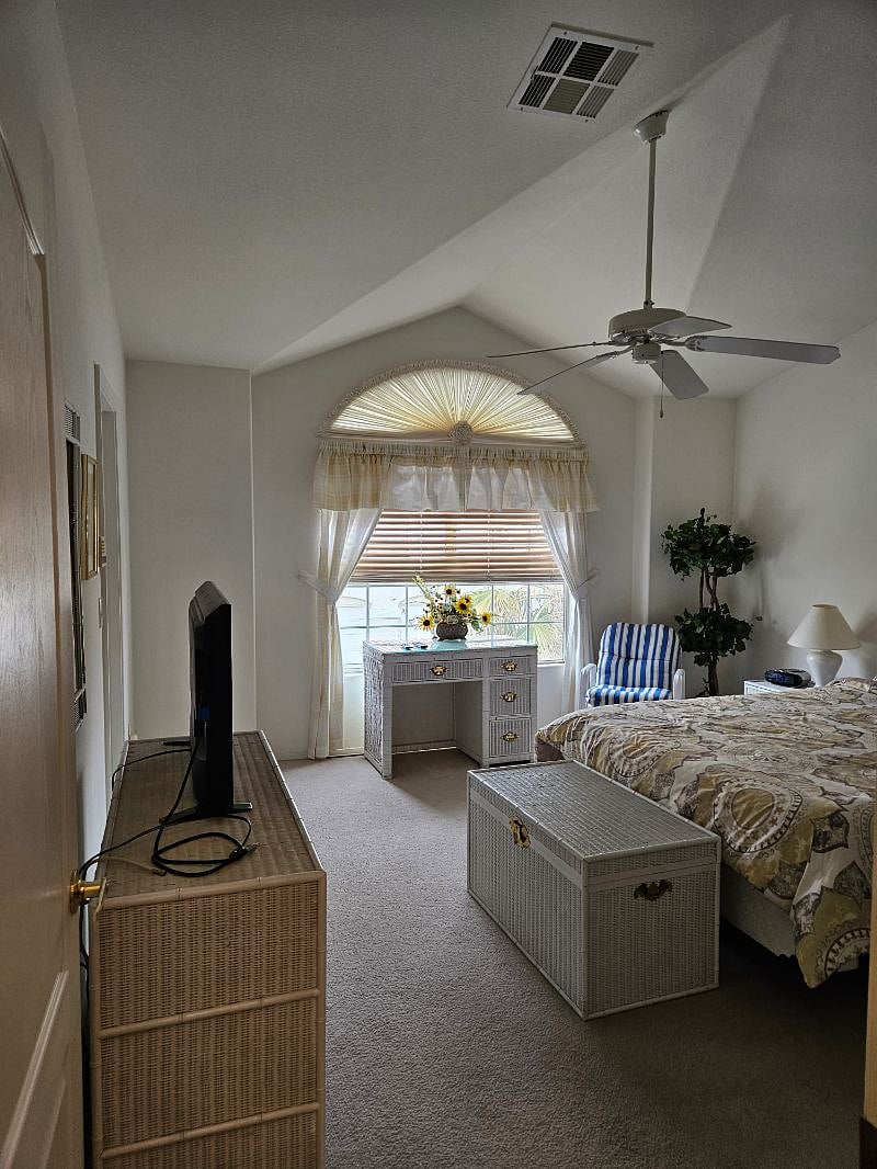 Primary bedroom with vaulted ceilings and ceiling fan