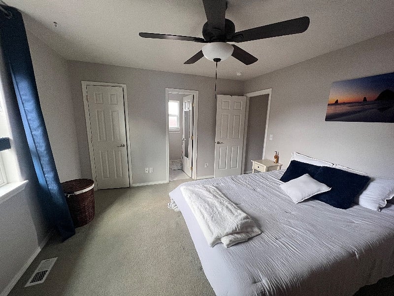 Master bedroom w/ queen bed, dresser, armoire, bathroom with a shower, ceiling fan, smart TV, and blackout curtains.