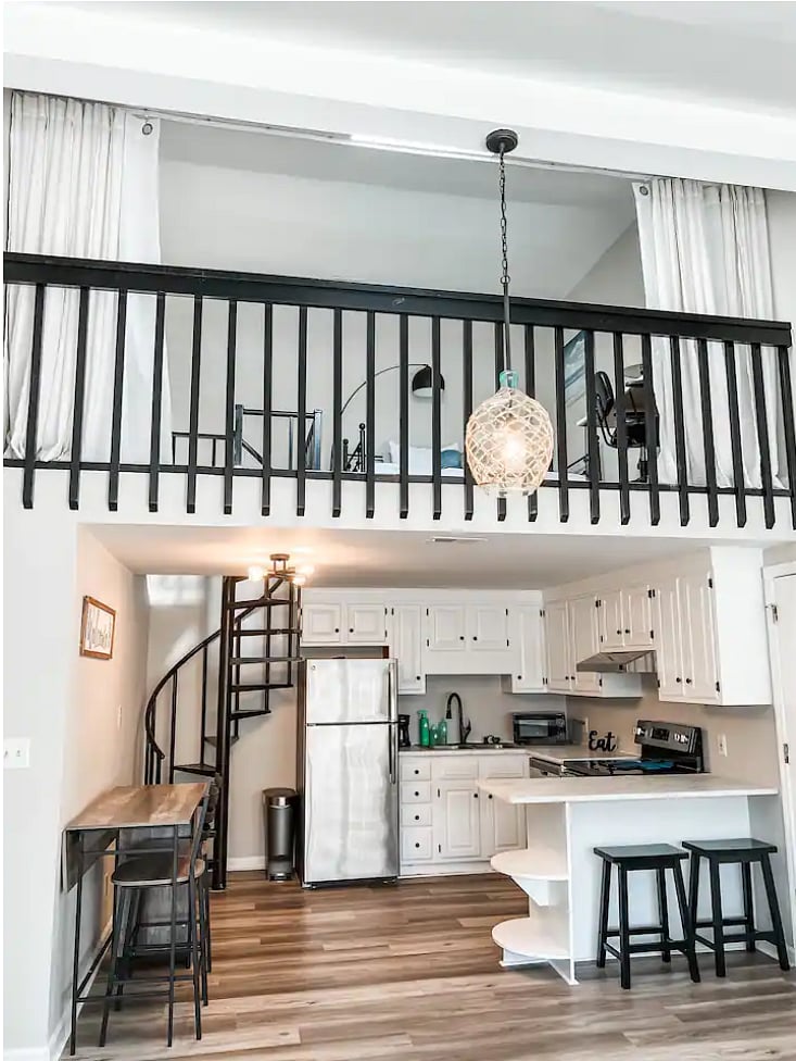 Overview of kitchen and 2nd floor loft with twin size bed, closet, and dedicated workspace. Linen curtains can be closed for privacy and light-filtering from above skylight when sleeping.
