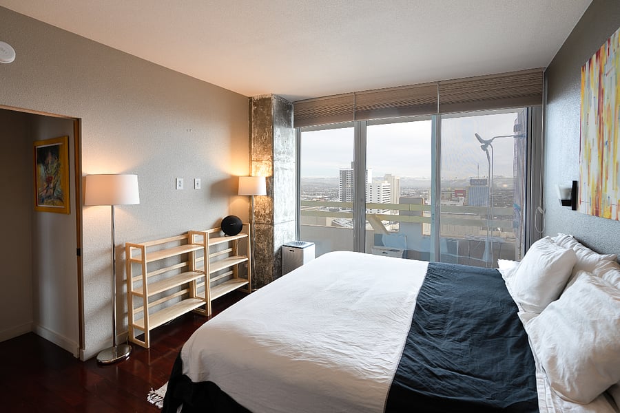 Master bedroom w/ en-suite bathroom, king bed, door to balcony.