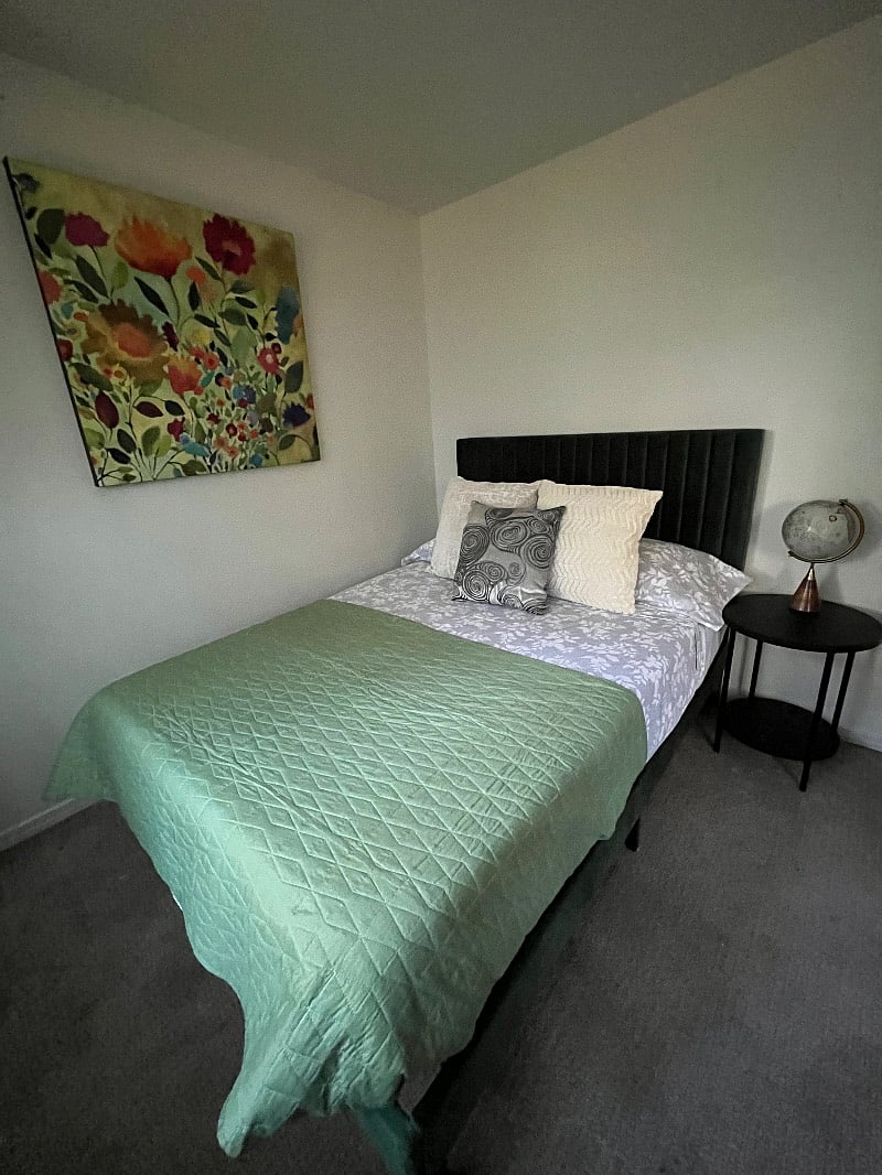 Second bedroom with green velvet full bed, large closet and large window.