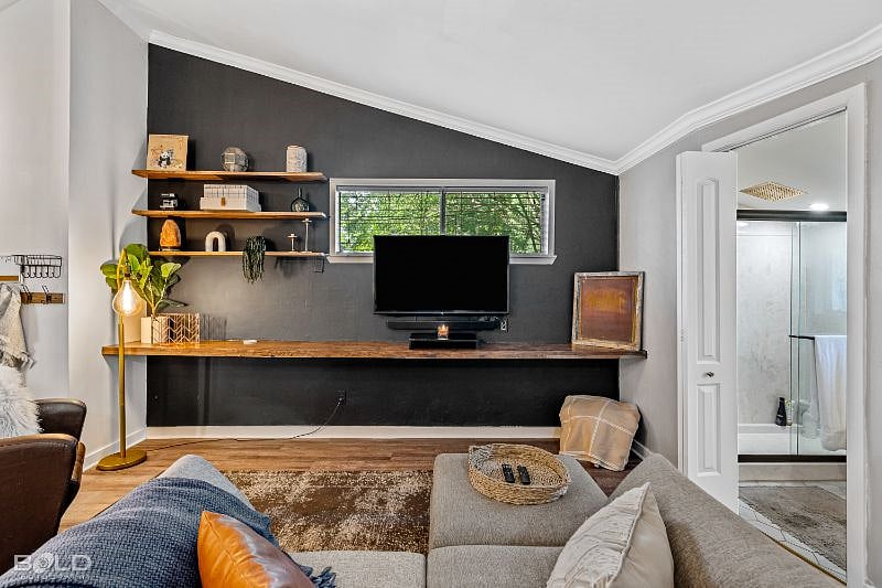Full view of the living area. Custom bookshelves create a workspace, living space, and entry area.