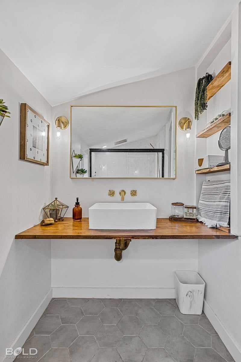 Fresh and bright, this newly remodeled bathroom has a floating sink with wall storage to the right. Fully stocked for your convenience.