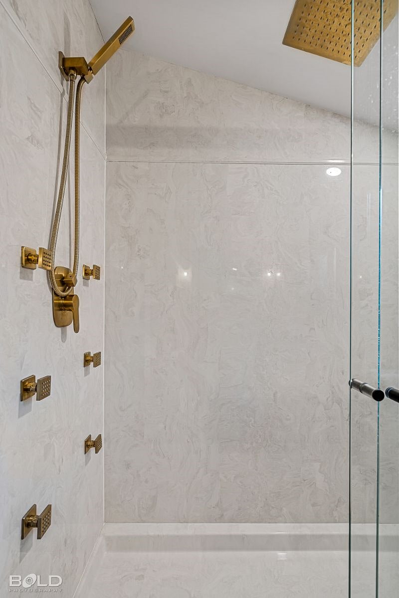Luxury oversized walk-in shower with marble surround. You'll find it is easy to relax and unwind here, with options for a rainhead, wall jet, or handheld shower.