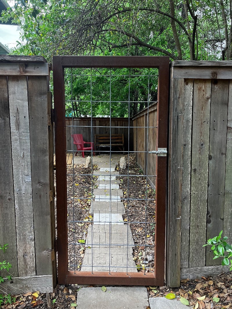 Gate entry into fenced shade garden.