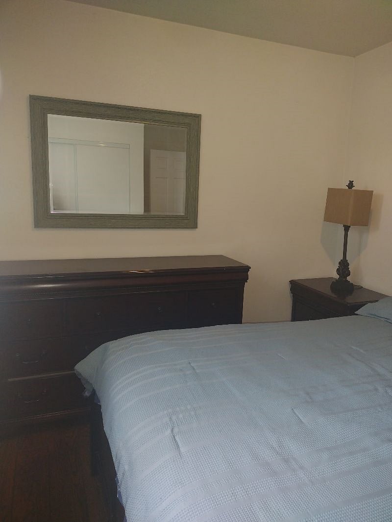 This bedroom is overlooking the patio, has a closet,  a queen size bed, with 4 drawers on the bottom, a dresser with 6 drawers, and two nightstands, and 2 drawers each. 