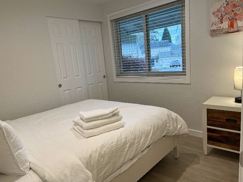 The second bedroom also features a queen-size bed; the window faces the front yard