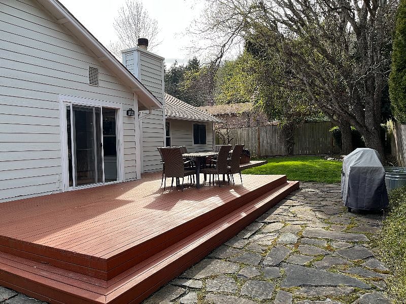 A spacious deck with an outdoor table, chairs, and a BBQ grill.