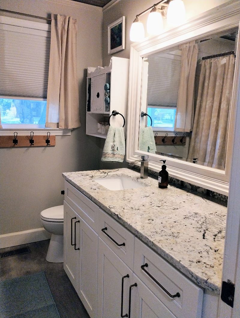 Hall guest bath features granite vanity. First aid supplies in the cabinet on the wall