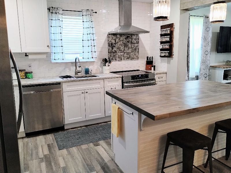 Induction / convection range oven with stainless vent Hood. Spice rack and subway tile backsplash.