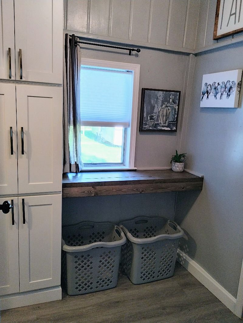 Mudroom has large pantry cabinet and folding table. Door opens to fence rear yard.