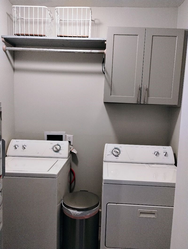 Laundry room has washer and dryer, hanging rod, shelf and cabinet