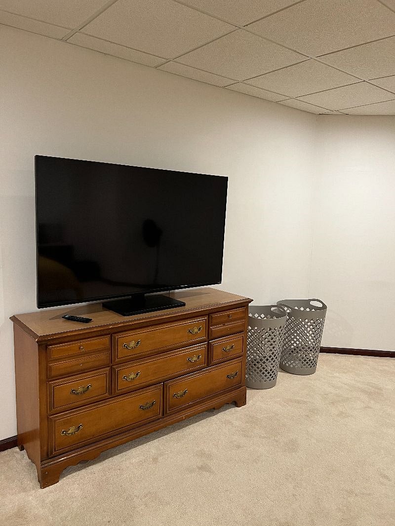 Master bedroom with dresser and 60" Smart television.