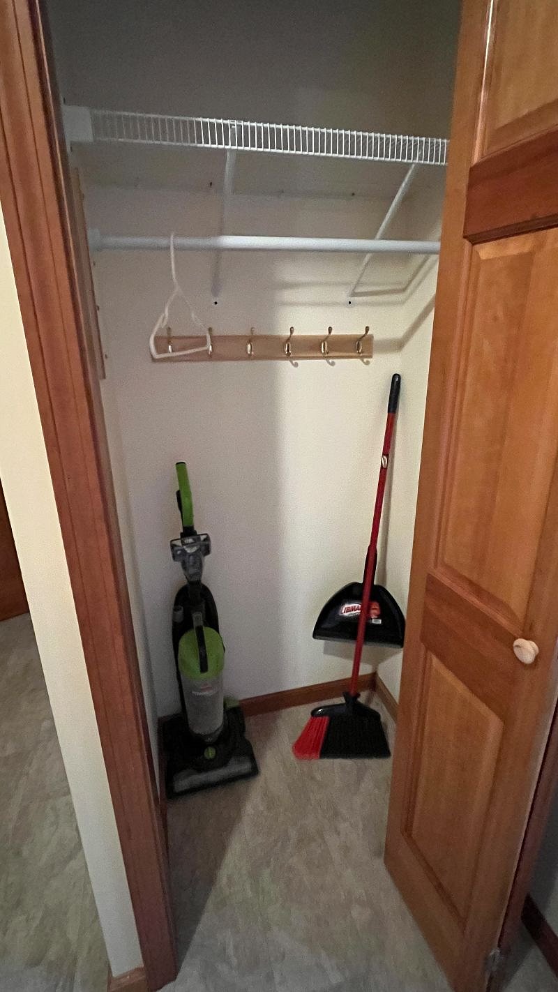Coat closet with vacuum and broom.
