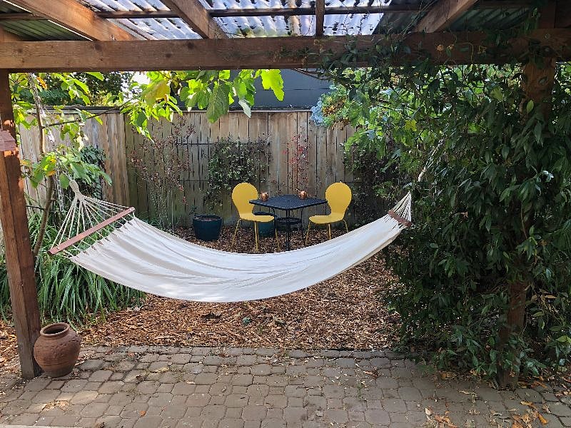 Covered porch with hammock set up and outdoor eating area.