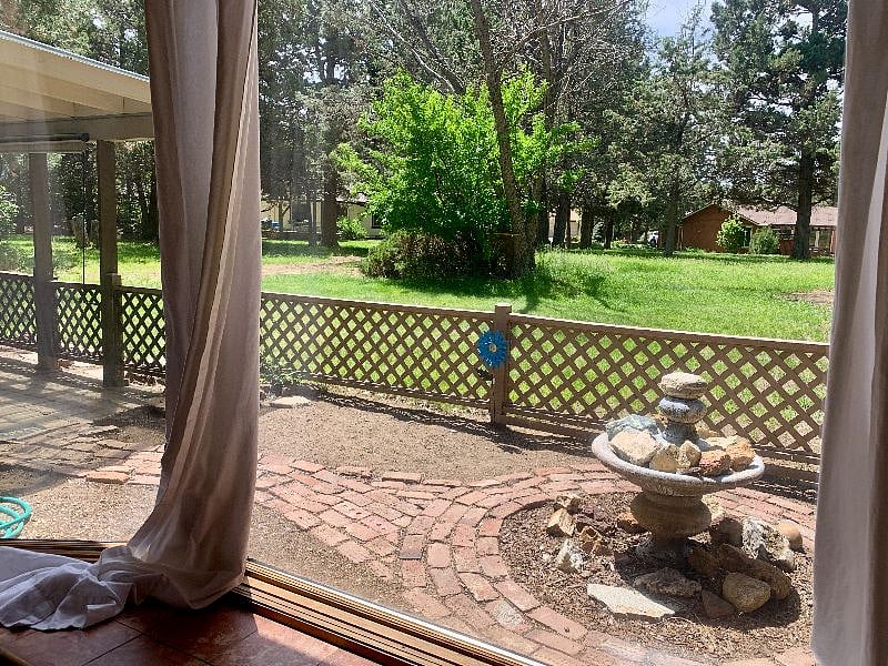 Charming, fenced back patio, has sitting areas/covered patios on each side with this walking path in between. View of the community open space behind.
