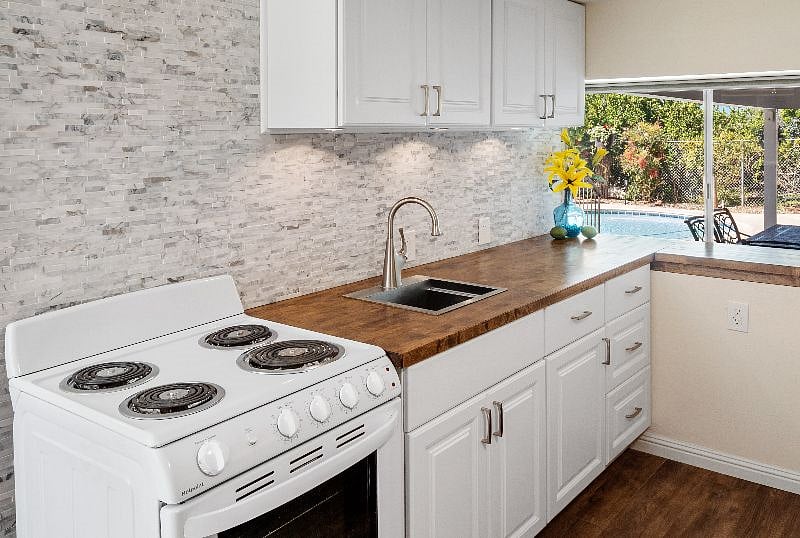 Newly remodeled kitchenette with stainless steel sink, butcherblock countertop and oven.