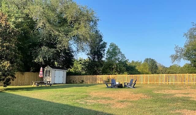 Picnic table with umbrella, firepit with seating area in large backyard