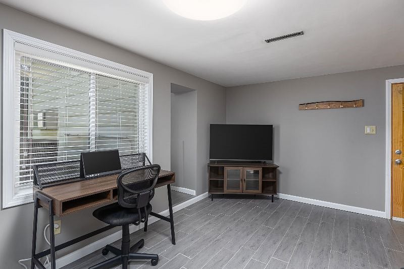 Lower level sitting area that is equipped with 50" smart tv and desk with 2nd monitor if needed. Hallway to workout area and door access to garage.