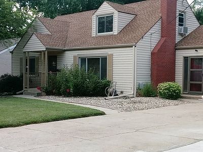 Front of the home in Summer. The door near the chimney is shared entrance near the driveway.