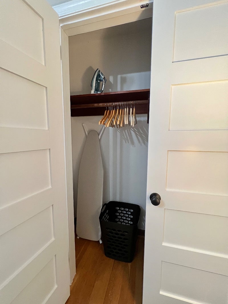 Large closets with ironing board, iron, wood hangers, & laundry baskets