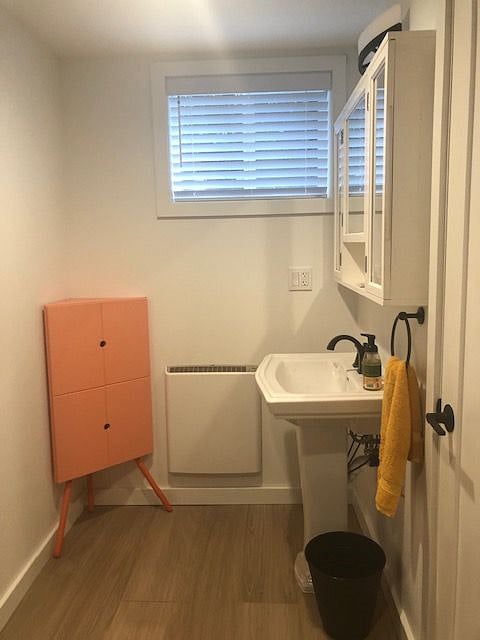 Sink area with medicine cabinet, pedestal sink and corner cabinet. Door opens to storage area under front porch. Window with screen and large slat venetian blinds for fresh air and privacy.