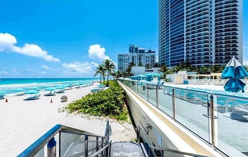 Beach in Front of Building with complimentary seats and umbrellas.